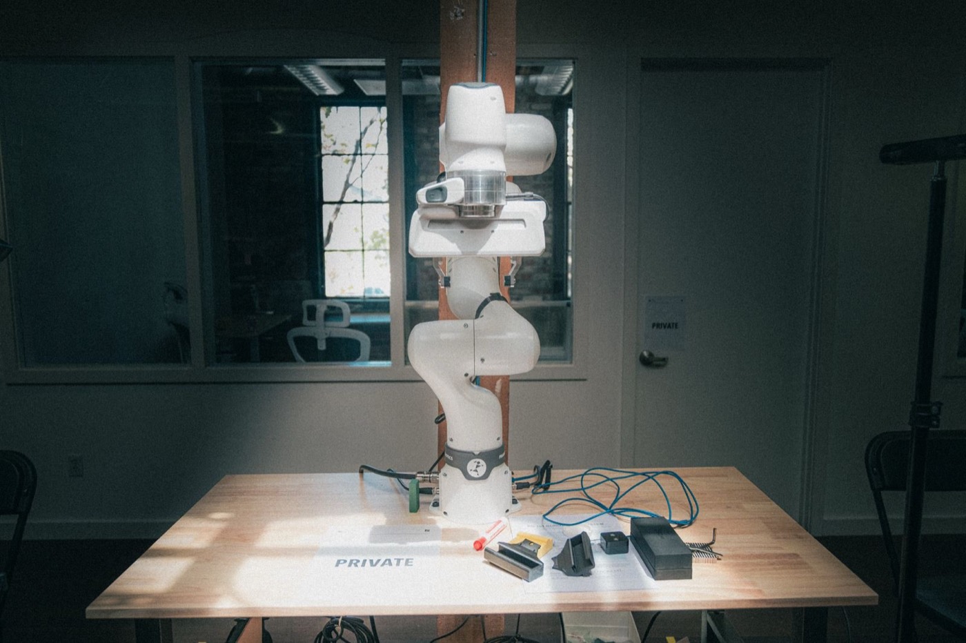 A robot arm parked on a workbench in the window light