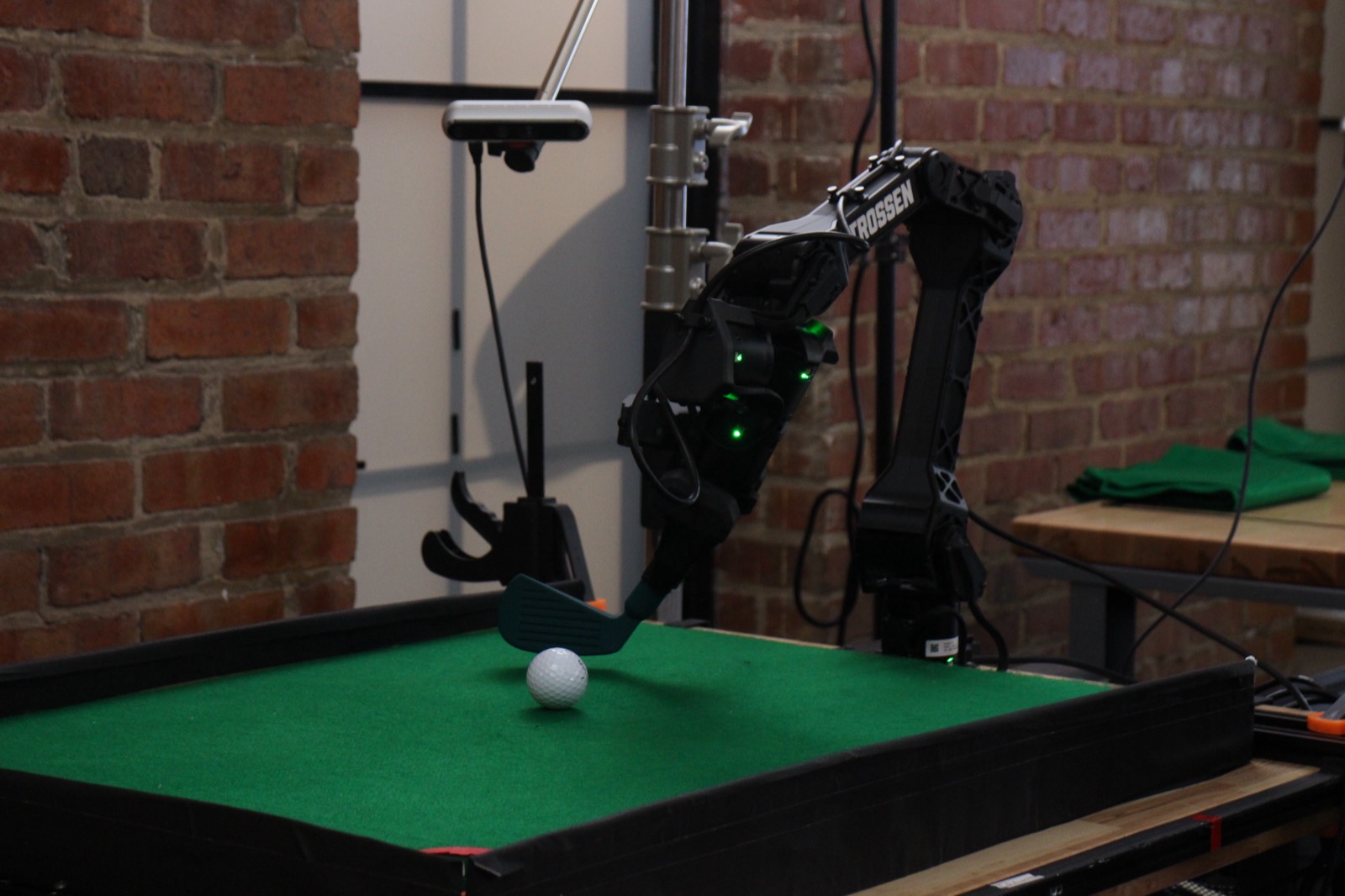 A Trossen arm running a putting task against the floor's exposed brick